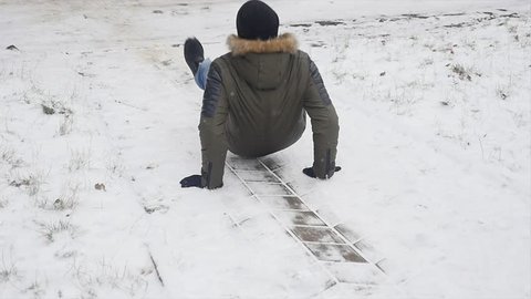Young stylishly dressed man while walking in the Park in winter slipped and lost his balance