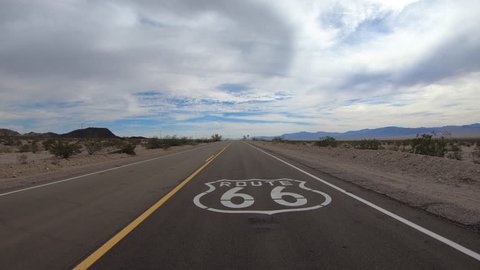 Low aerial fly over of historic Route 66 pavement sign in the scenic California Mojave desert.