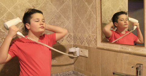 Boy drying hair in bathroom