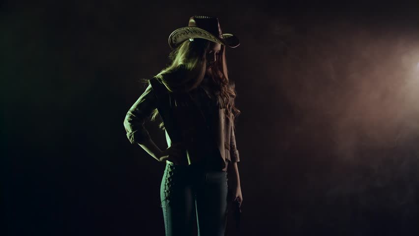 Cowboy girl takes out a revolver and makes a shot. Black smoke background. Slow motion. Side view