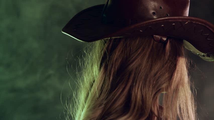 Sheriff girl holds a revolver in her hands and aiming at the villain. Black smoke background. Slow motion. Close up