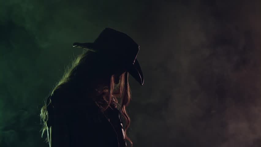 Cowgirl holds a revolver in her hands and aiming at the villain. Black smoke background. Slow motion. Side view. Silhouette