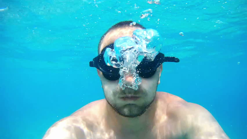 A young white handsome male doing an underwater selfie on an action camera. Portrait of a young man with glasses taking himself off to the camera under water. | Shutterstock HD Video #1007209786