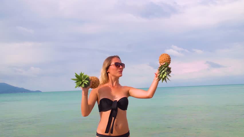 Young Woman with Pineapples Having Fun on the Beach
