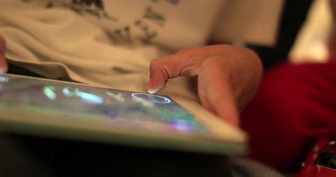 Close-up of child hands holding tablet playing games on device in 4K