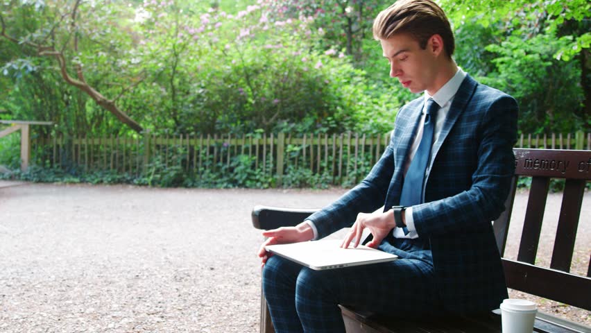 Stylishly Dressed Businessman Using Laptop In Park
