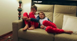 Boys seated on sofa watching TV off camera. 4K candid clip of children watching screen at home