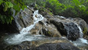 Tropical stream splashes over a rocky. natural waterfall in a Phuket. jungle wilderness area. 4k Ultra HD video with sound.