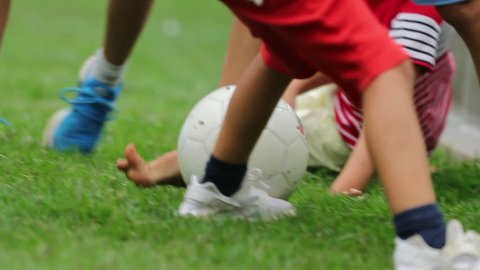 Child falling to the ground while playing soccer. Kid drops to the ground because in football match