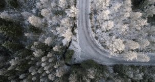 Frozen road, Cinema 4k aerial view above a frosty road, between frozen trees in a forest , on a sunny winter, day, in Uusimaa, Finland