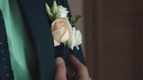 Groom adjusts wedding boutonniere. Clip. Groom boutonniere on a man corrects his pocket hand