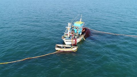 Professional fishing. The fishermen unwind and set the network in a circle, on the small blue fishing boat and dinghy. Big birds near a boats. Aerial view.