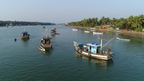 Aerial camera flight over several original indian fishing boats anchored in Sal river in Goa, India. Boats beautiful reflected in calm water in the river.