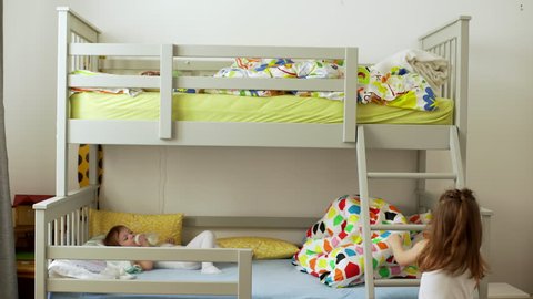 Picture of small two children resting in bedroom and lying in bunk bed with colorful bedding after awakening in morning