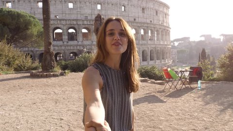 Beautiful young woman with long hair lead boyfriend by the hand towards colosseum in rome at sunset come with me attractive happy couple