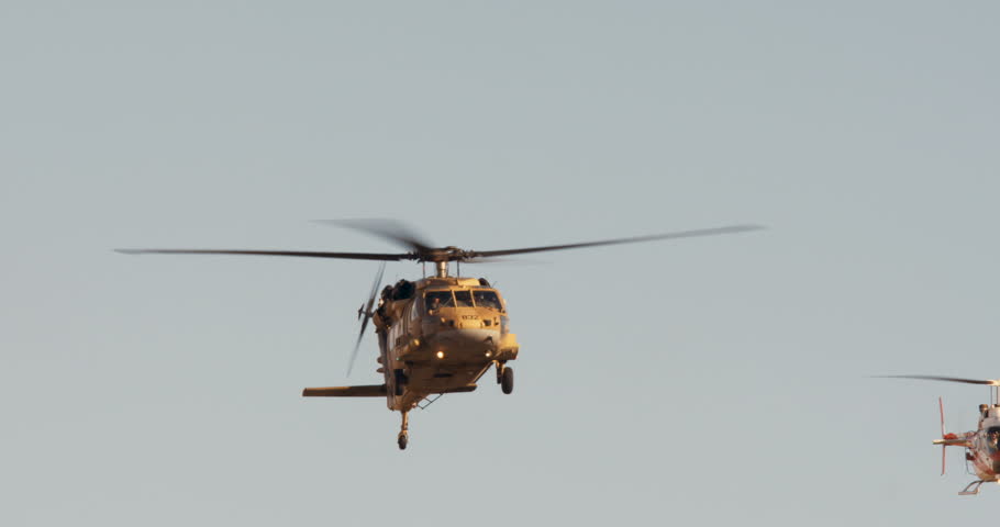 Two blackhawk helicopters fly in formation at low altitude