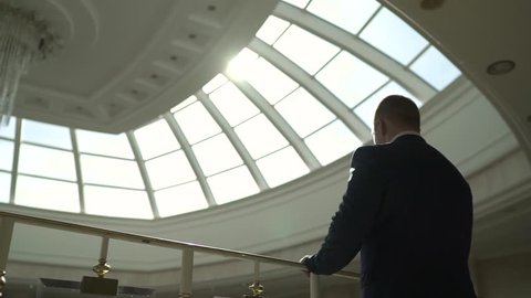 the businessman is standing on the balcony with his back. Businessman in suit