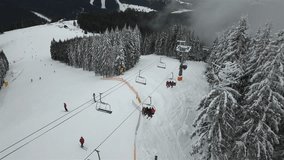 A ski lift in a forest in a ski resort raises people to the top of the mountains