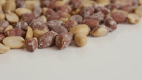 Arachis hypogaea salted snack close-up 4K 2160p 30fps UltraHD tilting footage - Pile of roasted peanuts on white background 3840X2160 UHD video