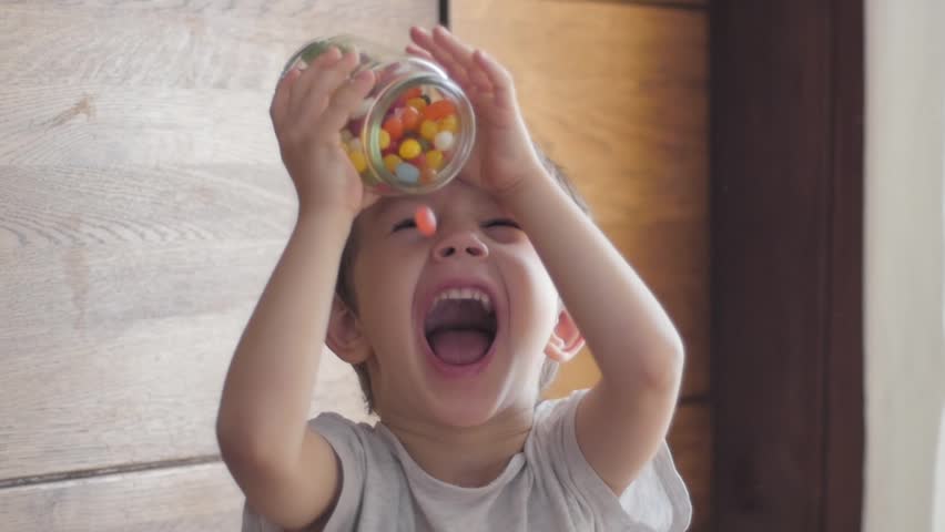 Boy eating candies falling from jar | Shutterstock HD Video #1007258500