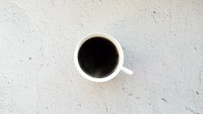 Serving coffee on a white cup. A cup of coffee on a white table, view from the top.
