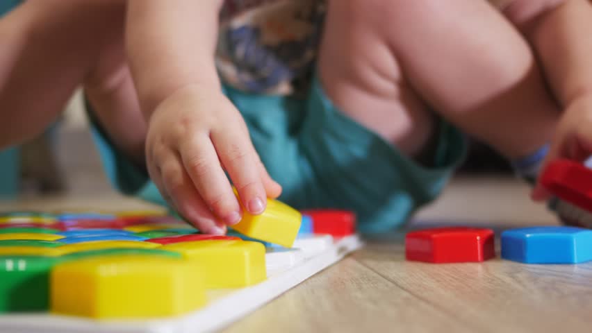 A cute child collects a picture from large multi-colored details. Playing with a puzzle Royalty-Free Stock Footage #1007265439