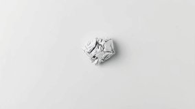 stop motion footage of flattening crumpled paper on white surface
