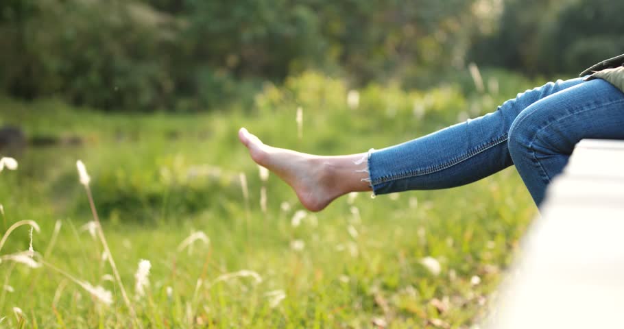 Woman sitting on the wooden edge of a wooden jetty and swing the legs