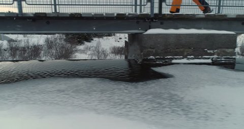 Pearson Walking on Bridge Above Dam in Winter. Frozen River. Iceland