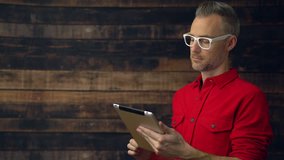 View of a thoughtful hipster in red shirt using tablet