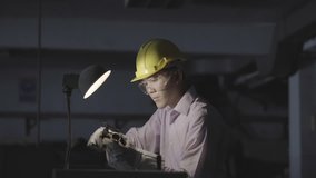 Asian young engineer working and using tools measurement quality of metal parts. Man wearing hardhat helmet safety with working workshop. Concept of engineering, career, industry, manufacture, securit