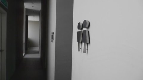 Bathroom restroom silver modern sign on white wall showing male and female symbols. Slow motion shot.