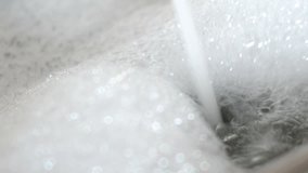 Flow of water into bath with foam. 4k UltraHD video