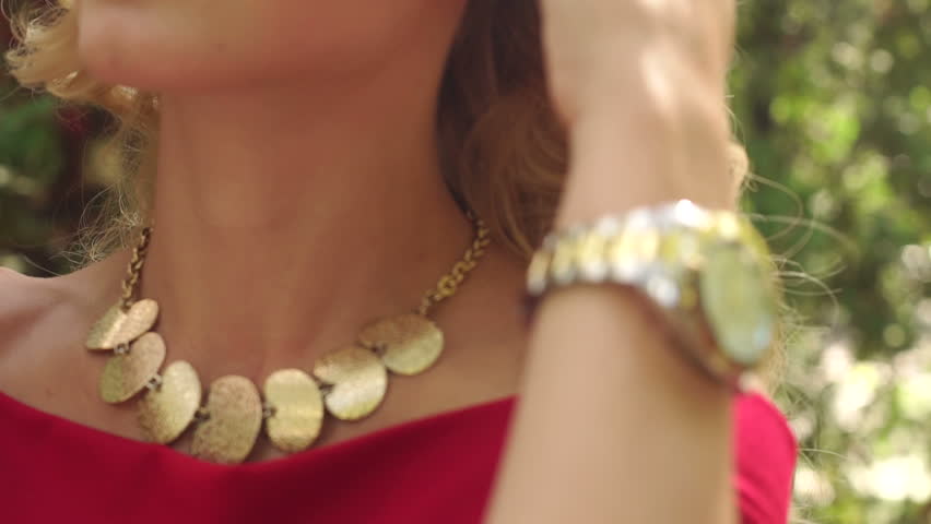 Close-up of a girl with jewelry and make-up outdoors in the Park on blurred green background.