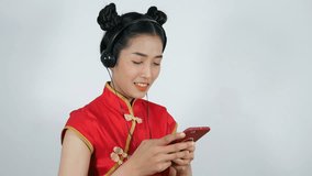 4k video of happy woman wear cheongsam and using mobile phone and listen to music