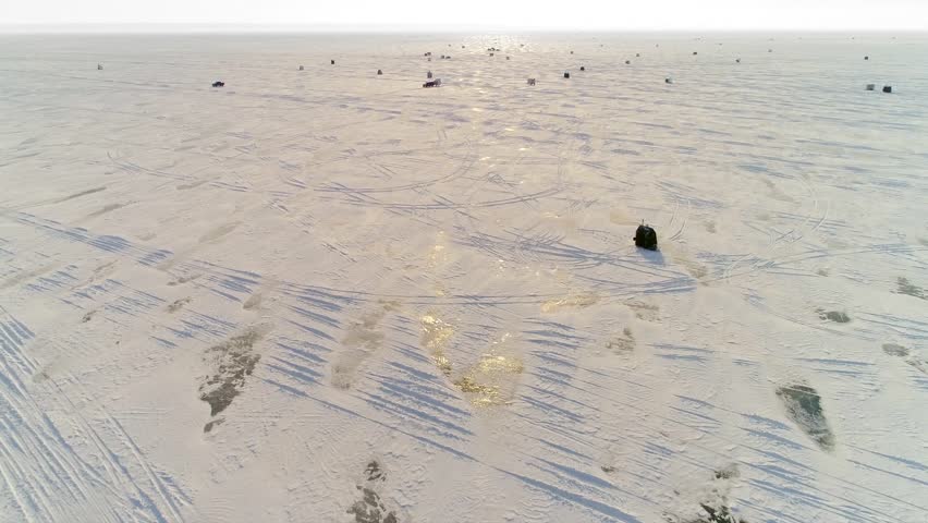 Low aerial flyover of ice fishing shanty village on vast Lake Winnebago, Wisconsin.
