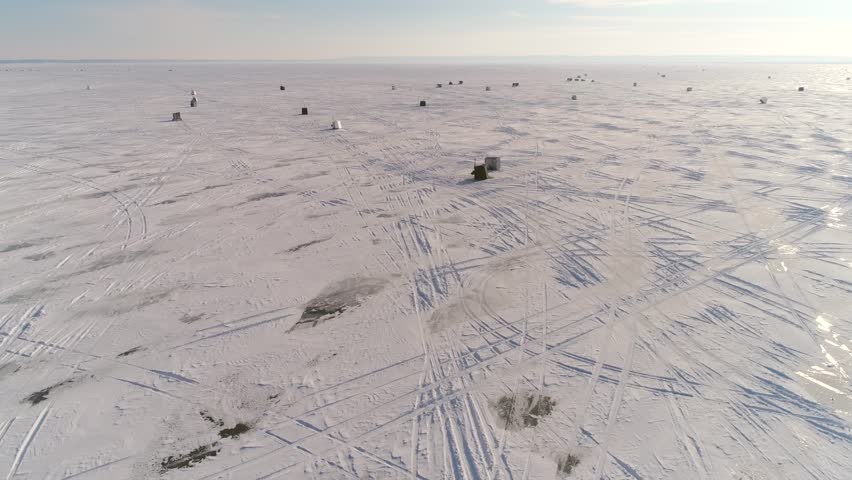 Low aerial flyover of ice fishing shanty village on vast Lake Winnebago, Wisconsin.
