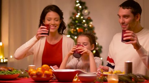 holidays, family and celebration - happy mother, father and little daughter having christmas dinner at home