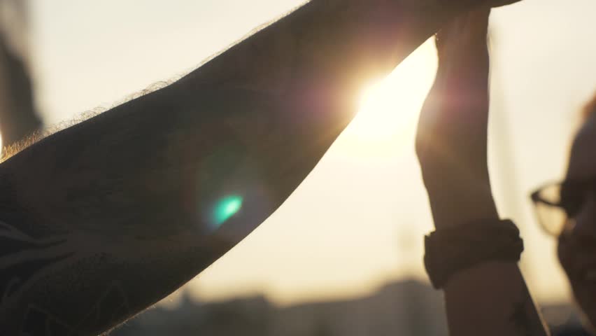 Happy woman and man giving five on sunny evening background close up