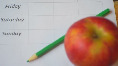 Diet Plan.
Ripe apples blank food schedule and pencil lie on a wooden table.View from above.Closeup