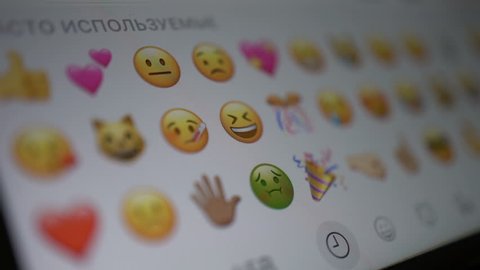 Samara, Russia - February 6, 2018: man looks at the emoji icons on a iphone. Emoji is a graphic language, where pictures are used instead of words