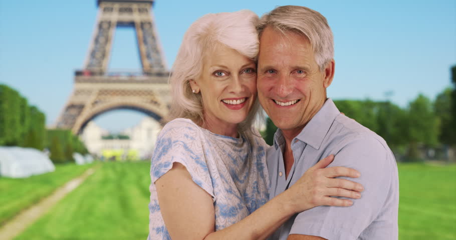 Attractive mature couple pose for a portrait in front of the Eiffel Tower. Happy male and female in Paris smiling at camera. 4k