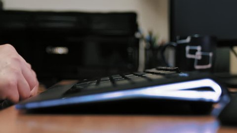 Man typing on modern illuminated computer keyboard.