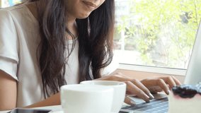 Beautiful asian woman drink coffee while using notebook computer at coffee shop