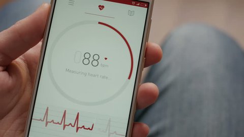 Man Looking At Health Monitoring App On Smartphone. Monitoring the heart pulse with a health application on smartphone.