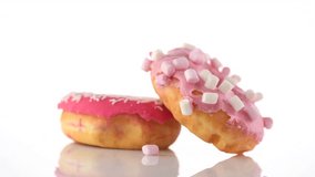 Donuts isolated on white background. Rotated Tasty pink glazed donuts closeup. Doughnut rotated on white. 4K UHD video