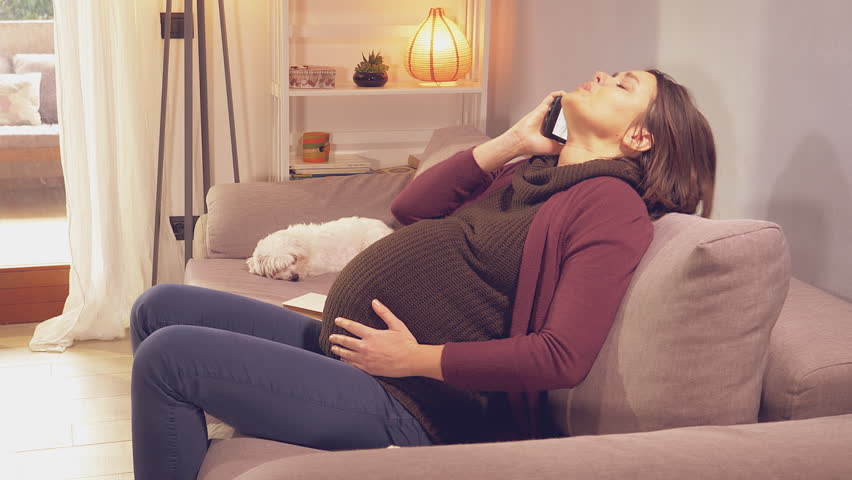 Pregnant woman sitting on sofa with contractions calling husband for help retro style | Shutterstock HD Video #1007343949