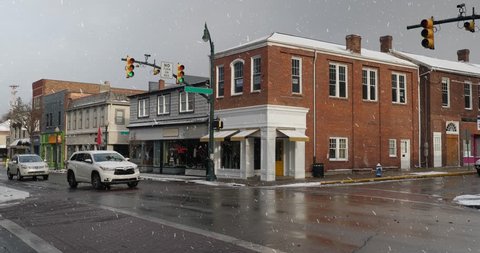 A daytime winter establishing shot of businesses on a typical Main Street in America. Building names obscured for general use. Light snow falling. Pittsburgh suburb.	 	