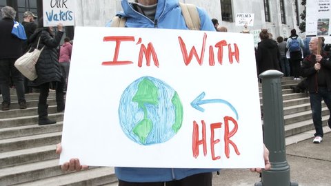 SALEM, OREGON - FEBRUARY 2018: Woman holding sign at state capitol rally reading "I'm With Her" in support of clean energy and to fight global warming.