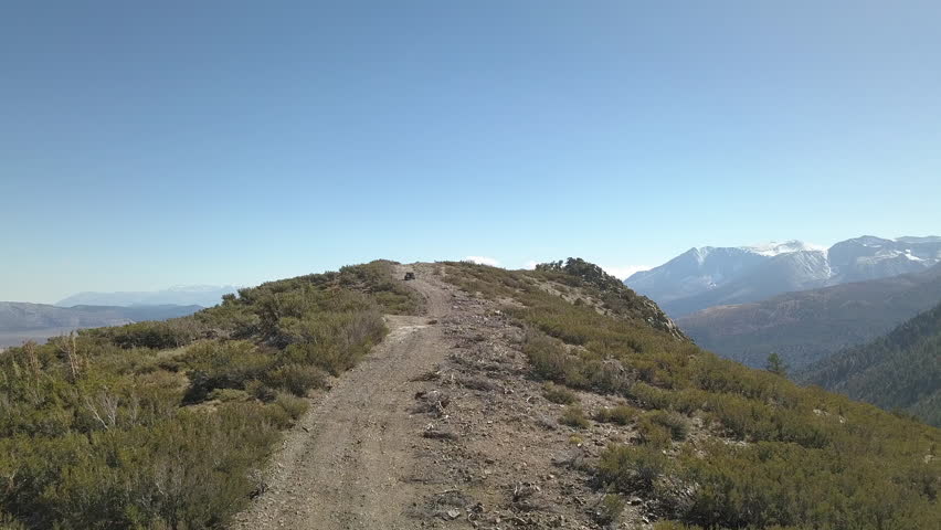 Aerial 4x4 ATV driving off road to top of mountain peak Mono Lake California